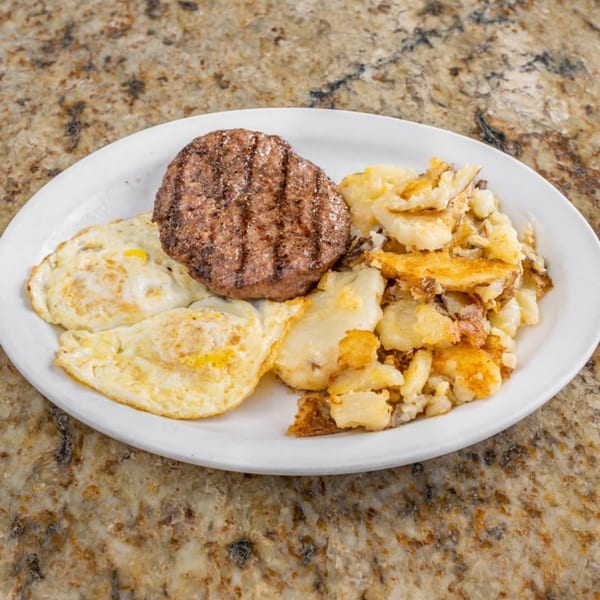 A breakfast plate with a grilled hamburger patty, two fried eggs, and a pile of home fries.